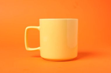 Turuncu arka planda bir sarı seramik bardak.