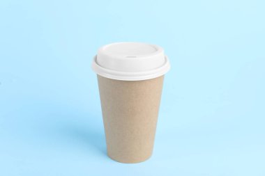 Açık mavi arka planda plastik kapaklı kağıt bardak. Kahve hazır.