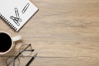 Bir bardak içki, bardaklar ve ahşap masadaki farklı kırtasiye malzemesi, mesaj için yeri olan düz bir yer. Merkez Ofis