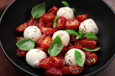 Domatesli Caprese salatası, mozzarella topları ve kasede fesleğen, yakın plan.