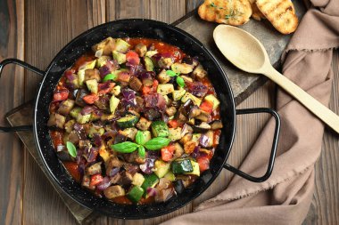 Ahşap masada servis edilen fırında leziz ratatouille.