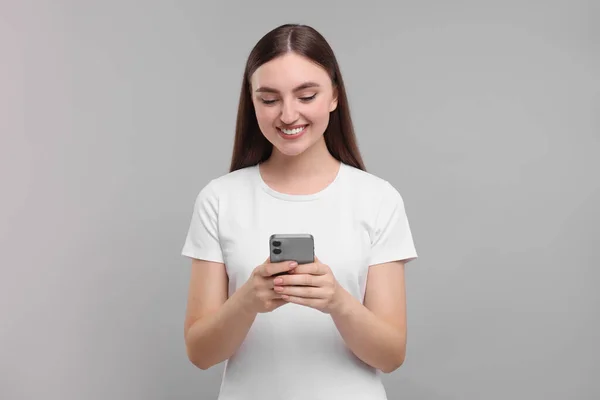 Усміхнена Жінка Використовує Смартфон Світло Сірому Фоні — стокове фото