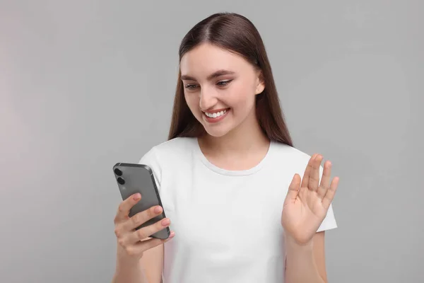 Uśmiechnięta Kobieta Mając Wideo Przez Smartfona Jasnoszarym Tle — Zdjęcie stockowe