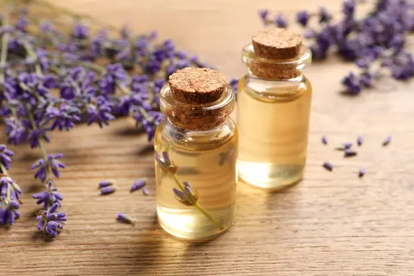 Essential oil and lavender flowers on wooden table, closeup