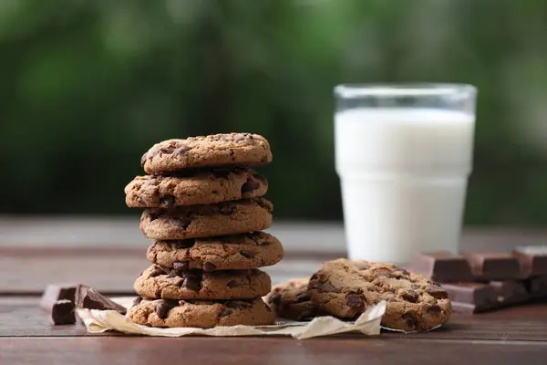 Delicious chocolate chip cookies and glass of milk on wooden table