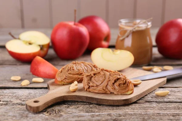 Fresh apples with peanut butter on wooden table