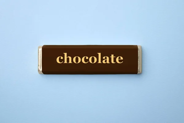ライトブルーの背景 トップビューに包装中のチョコレートバー — ストック写真