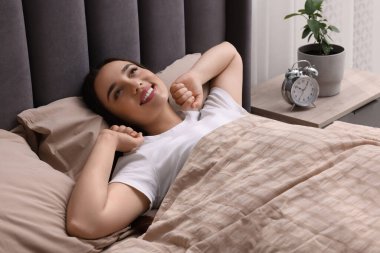 Evdeki yumuşak yatakta uzanan güzel bir kadın.
