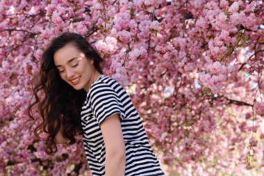 Bahar günü çiçek açan sakura ağacının yanında güzel bir kadın.