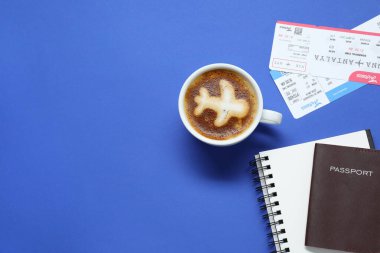 Pasaportlu düz kompozisyon, bir fincan kahve ve mavi masaya bilet, mesaj için yer. İş gezisi
