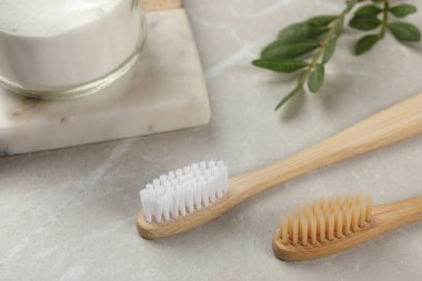 Bambu diş fırçaları ve bir kavanoz kabartma tozu açık gri mermer masada, yakın plan.