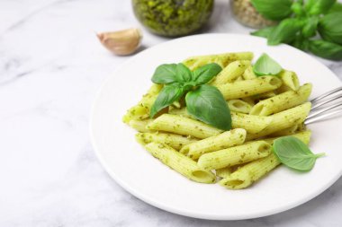 Pesto soslu lezzetli makarna ve beyaz mermer masada fesleğen, yakın plan. Metin için boşluk