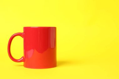 Sarı arkaplanda bir kırmızı seramik bardak, metin için boşluk
