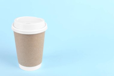 Açık mavi arka planda plastik kapaklı kağıt bardak, metin için boşluk. Kahve hazır.