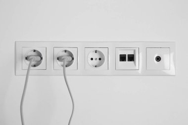 Beyaz duvarda fiş, ethernet ve TV coax plakalı birçok güç prizi var.