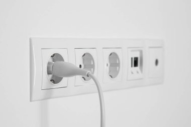 Beyaz duvarda fiş, ethernet ve TV coax plakalı birçok güç prizi var.