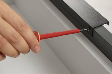 Kapalı alanda tornavidalı bir kadın çekmeceyi kuruyor.