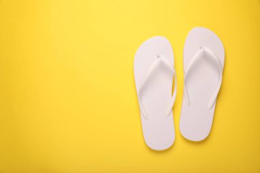 Sarı arka planda şık parmak arası terlikler, üst manzara. Metin için boşluk