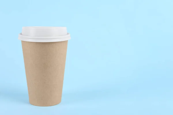 Paper cup with plastic lid on light blue background, space for text. Coffee to go