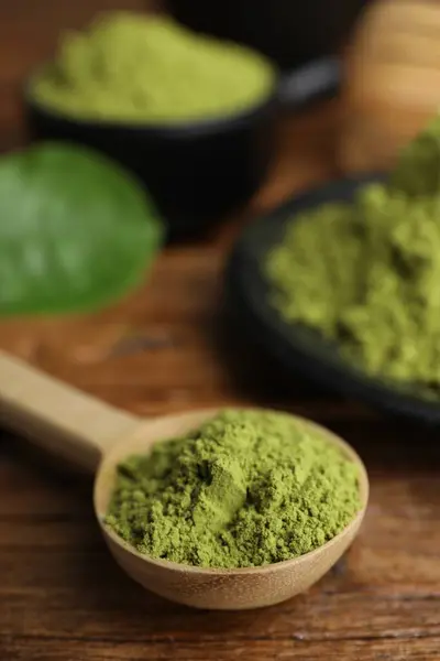 Scoop with green matcha powder on wooden table, closeup. Space for text