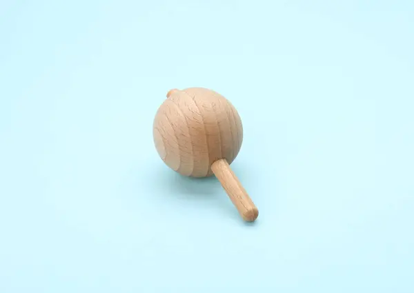 stock image One wooden spinning top on light blue background. Toy whirligig