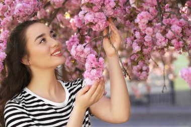 Bahar günü çiçek açan sakura ağacının yanında güzel bir kadın.