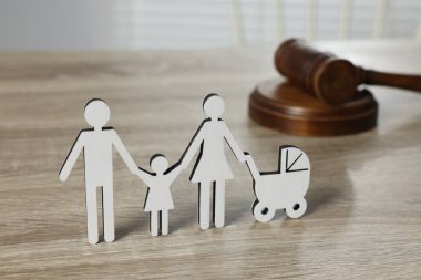 Aile hukuku. Çocuklu ebeveyn figürü ve açık ahşap masada tokmak.