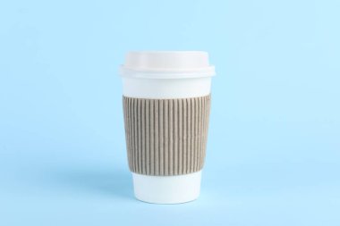 Açık mavi arka planda plastik kapaklı kağıt bardak. Kahve hazır.