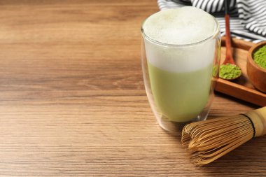 Bir bardak lezzetli matcha latte ve ahşap masa üzerinde bambu çırpıcı, metin için yer