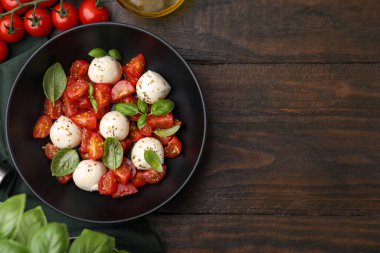 Domatesli Caprese salatası, mozzarella topları ve ahşap masada fesleğen. Metin için boşluk