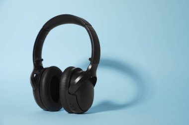 Açık mavi arka planda modern kablosuz kulaklıklar. Metin için boşluk