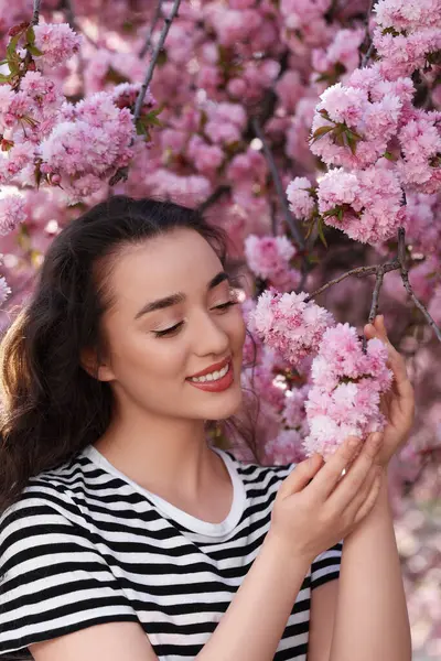 Bahar günü çiçek açan sakura ağacının yanında güzel bir kadın.