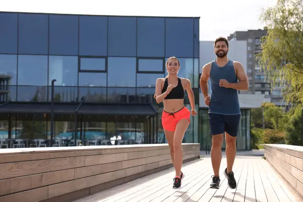 Healthy lifestyle. Happy couple running outdoors on sunny day, space for text