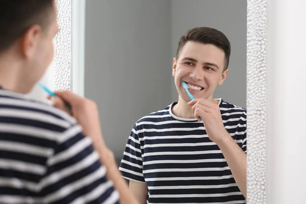 トイレの鏡の近くに歯ブラシで歯磨きをする男 — ストック写真