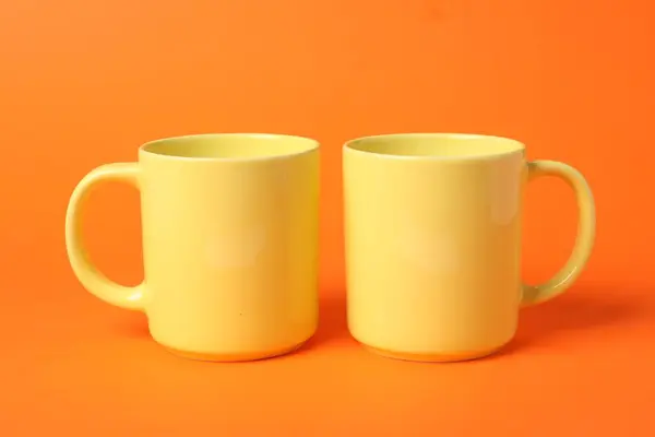 Дві Жовті Керамічні Чашки Помаранчевому Фоні — стокове фото