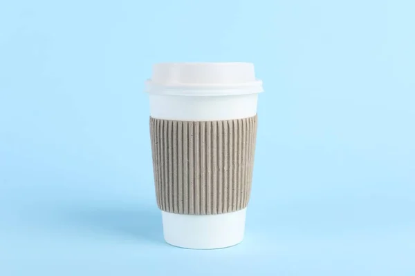 Paper cup with plastic lid on light blue background. Coffee to go