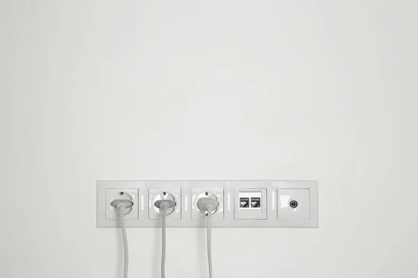 许多带有插头 以太网和电视诱发电位的电源插座在室内白墙上 案文的篇幅 — 图库照片