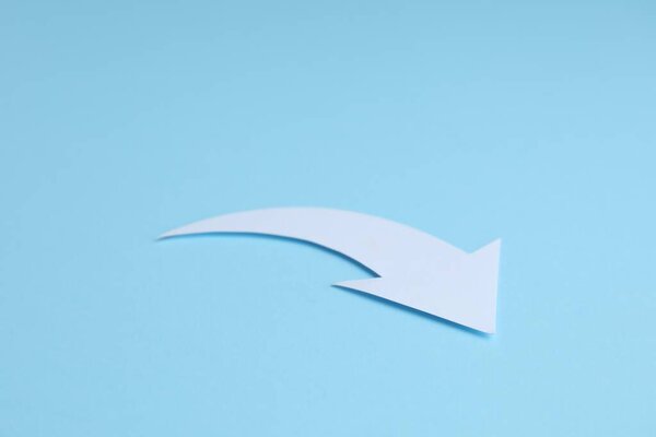 White curved paper arrow on light blue background