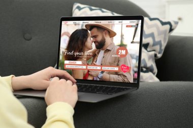 Ortak arıyorum. Evde dizüstü bilgisayar kullanan bir kadın, yakın çekim. Aygıt ekranındaki randevu sitesi web sayfası