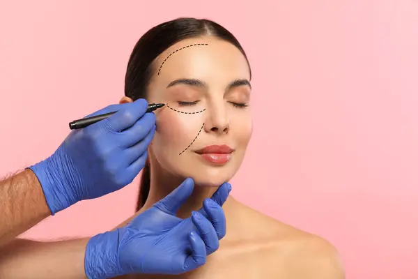 Žena Připravuje Kosmetickou Operaci Růžové Pozadí Doktorské Kresby Její Tváři — Stock fotografie