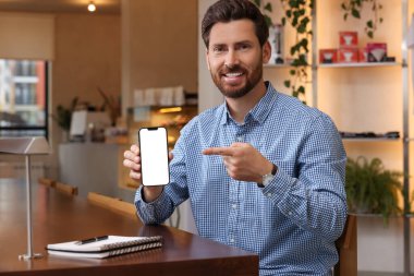 Kafede akıllı telefonunu gösteren yakışıklı bir adam.