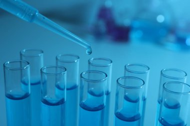 Test tüpüne mavi sıvı damlatılıyor, yakın plan. Laboratuvar analizi