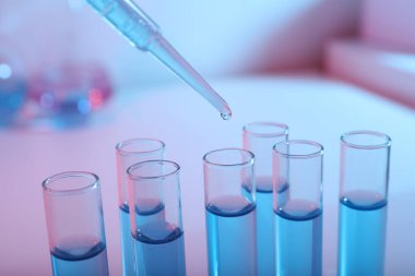 Test tüpüne mavi sıvı damlatılıyor, yakın plan. Laboratuvar analizi
