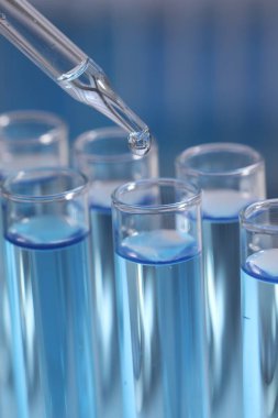 Bulanık arkaplanda test tüpüne reaktör damlatılıyor, yakın plan. Laboratuvar analizi