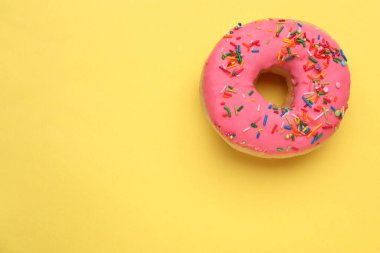 Sarı zemin üzerine serpiştirilmiş jöleli donut, üst manzara. Mesaj için yer var. Lezzetli şekerlemeler.
