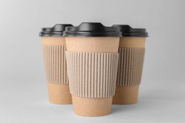 Açık gri arka planda siyah kapaklı kağıt bardaklar. Kahve hazır.