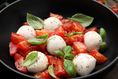 Domatesli Caprese salatası, mozzarella topları ve kasede fesleğen, yakın plan.