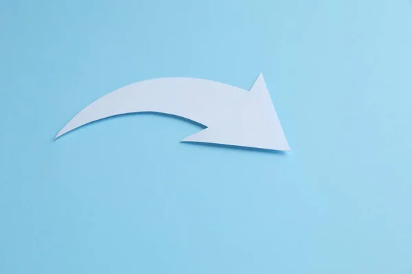 White curved paper arrow on light blue background, space for text