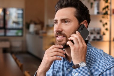 Kafede telefonla konuşan yakışıklı bir adam.