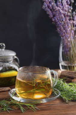 Ev yapımı bitki çayı ve ahşap masada taze tarhun yaprağı.
